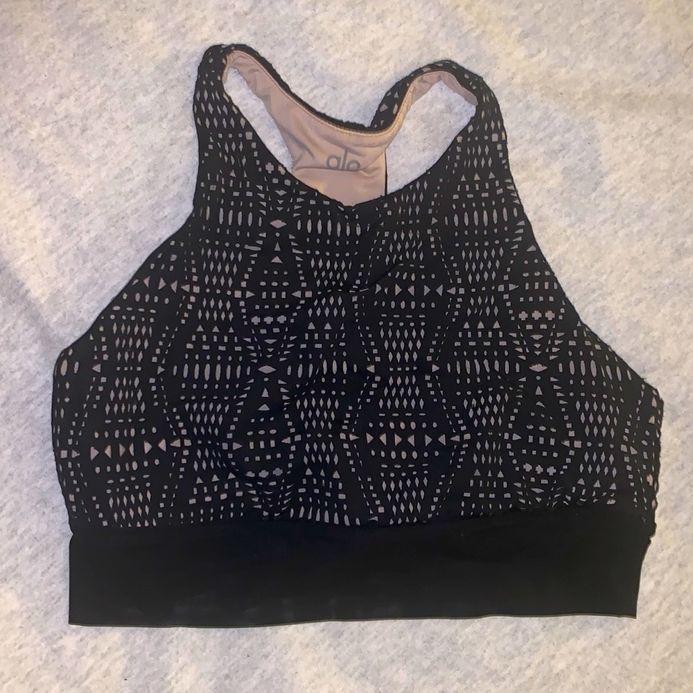 Alo Yoga sports bra in black. Cut out design throughout with mesh at the bottom